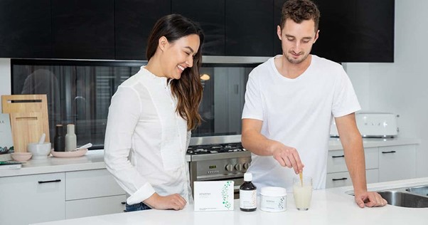 male and female in white tops smiling talking about products on counter