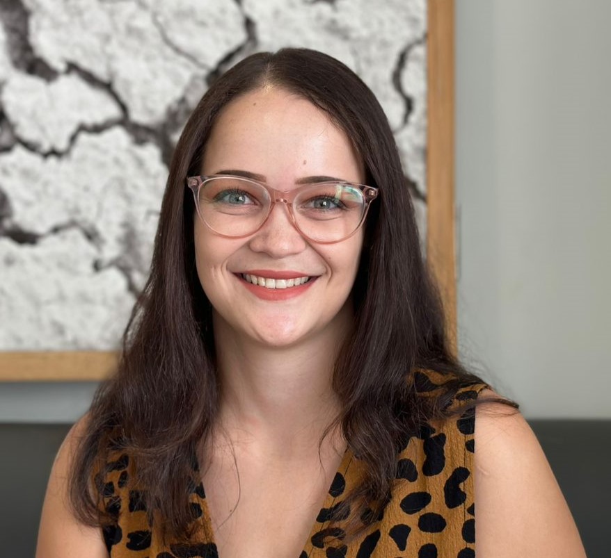 Long hair brunette female smiling at camera wearing glasses