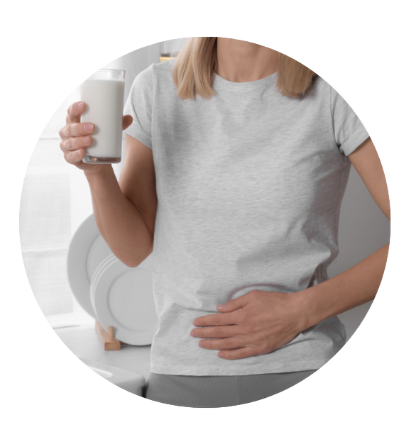 blond female hand on stomach holding glass of milk